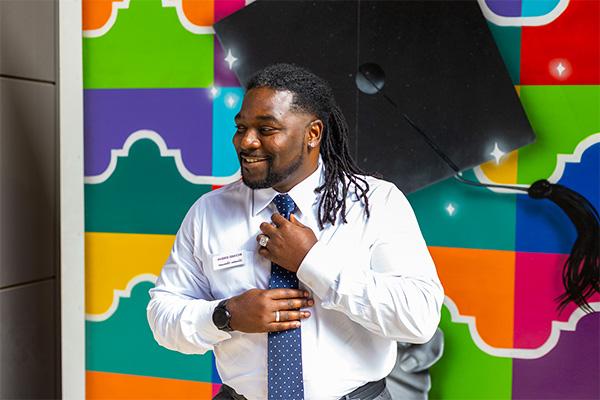 Richard Jordan posing in front a street painting mural of alamo colleges district logos